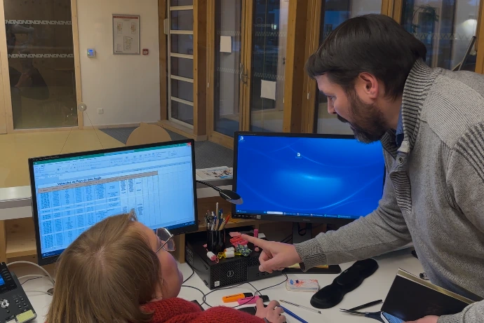 Homme pointant du doigt l'écran du poste de travaille d'une dame