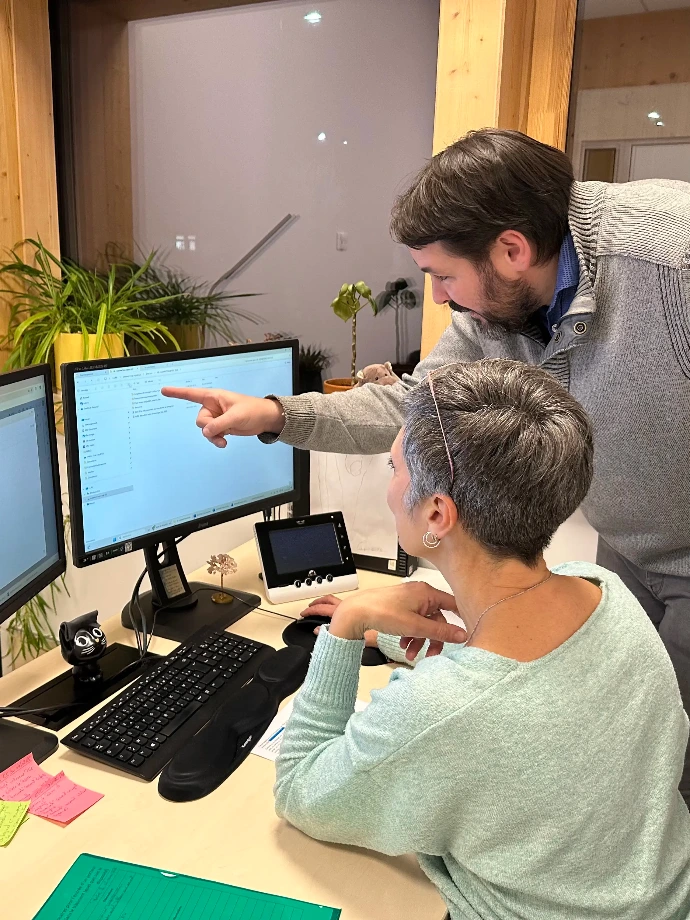 Homme pointant du doigt l'écran du poste de travaille d'une dame